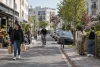 Des habitants circulent dans une rue résidentielle ordinaire et paisible en journée.
